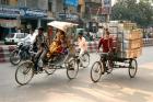 People and cargo move through streets via rickshaw, Varanasi, India