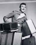 1950s Smiling Bellboy Carrying Four Bags Of Luggage
