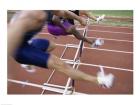 Side profile of three people jumping a hurdle