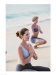 Young woman and a mid adult woman meditating on the beach