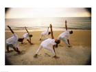 Group of people performing yoga on the beach