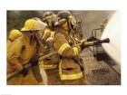 Side profile of a group of firefighters holding water hoses