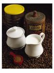 Close-up of a mug of milk with a measuring spoon and jars on coffee beans