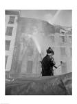 Firefighter pouring water on burning building, low angle view