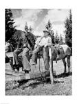 Teenage cowboys sitting on rail fence