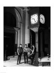 Young men standing below clock at night