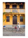 Person riding a bicycle in front of a cafe, Hoi An, Vietnam
