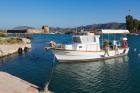 Butrint, Albania. Fishing boat moored in the Vivari Channel front of the archeological site. In the background the 16th century triangular fortress. Part of a National Park and a UNESCO World Heritage Site. (photo)