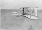 Wilbur in prone position in damaged machine on ground after unsuccessful trial in North Carolina, USA, 1903