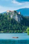 Lake Bled, Upper Carniola, Slovenia. Bled Castle seen across the lake. Couple enjoying outing in rowing boat.