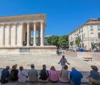 Nimes, Gard Department, Languedoc-Roussillon, France. A tour guide gives her group details of the first century BC Roman temple known as Maison Carree.