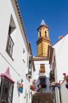 Estepona, Costa del Sol, Malaga Province, Andalusia, southern Spain. Church. Tower of Iglesia de Nuestra Señora de los Remedios church seen at end of Calle Murillo.