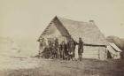 A group of soldiers, and two young men, one an African American, stand outside of log cabin quarters, 1861-65 (b/w photo)