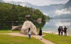 Lake Bohinj (Bohinjsko jezero), Triglav National Park, Upper Carniola, Slovenia. Visitors admiring the lake in the early morning at the site of the statue of Zlatorog. Zlatorog is a mythical chamois with golden horns immortalized by German poet Rudolf Bau