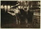 8 year old Leo, only 4 feet tall, picks up bobbins for 15 cents a day at Elk Cotton Mills, Fayetteville, Tennessee, 1910 (b/w photo)