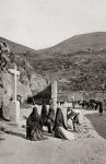 Women kneeling in front of cross in a roadside scene in Spain circa 1900