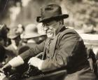 Theodore Roosevelt smiling from an automobile (b/w photo)