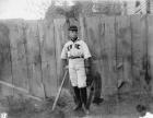 Boy in baseball uniform by fence