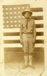 World War I soldier with American flag in background, 1914-18 (b/w photo)