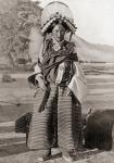 A woman from western Tibet wearing traditional dress. The headdress is covered with pearls, coral, turquoise and other uncut precious stones and glass beads. Each stone has a special protective property against evil spirits. The necklace carries an amulet