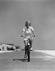 1940s Summer Time Smiling Woman Riding Bike On Beach Boardwalk | Obraz na stenu