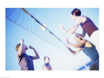 Low angle view of two young couples playing beach volleyball | Obraz na stenu