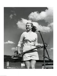 Young woman standing on boat, holding anchor | Obraz na stenu