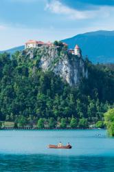 Lake Bled, Upper Carniola, Slovenia. Bled Castle seen across the lake. Couple enjoying outing in rowing boat. | Obraz na stenu