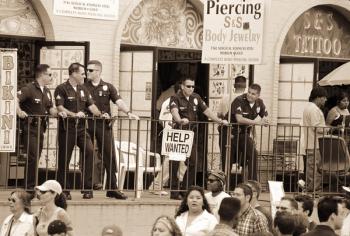 Police gathered behind a 'Help Wanted' sign, 2004 (b/w photo) | Obraz na stenu