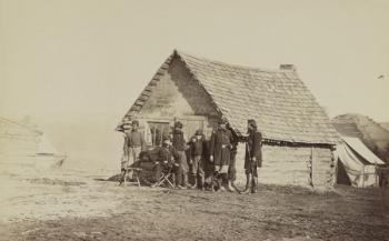 A group of soldiers, and two young men, one an African American, stand outside of log cabin quarters, 1861-65 (b/w photo) | Obraz na stenu