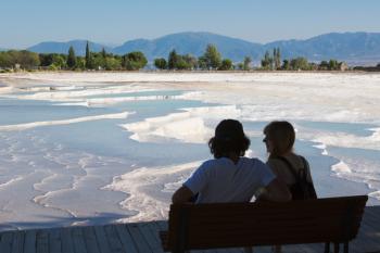 Pamukkale, Denizli Province, Turkey. A couple looking out over the white travertine limestone terraces and pools. Pamukkale is known as the Cotton Castle. It is a UNESCO World Heritage Site. | Obraz na stenu