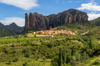 Village of Agüero beneath the conglomerate rock formations of the Mallos de Riglos, Huesca Province, Aragon, Spain. The Mallos de Riglos are approximately 300 meters high. The area is popular with climbers. (photo) | Obraz na stenu