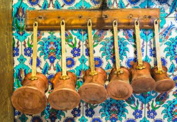 Istanbul, Turkey. Various sized pots for preparing Turkish coffee hanging in a cafe kitchen. Typical tiles on wall. | Obraz na stenu