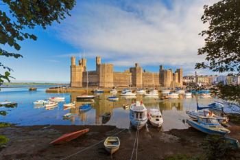 Caernarfon or Carnarvon or Caernarvon, Gwynedd, Wales, United Kingdom. Caernarfon Castle seen across the River Seiont. It is part of the UNESCO World Heritage Site which includes a group of Castles and Town Walls of King Edward in Gwynedd. Harlech and Bea | Obraz na stenu